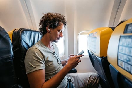 tall man on airplane using headphones