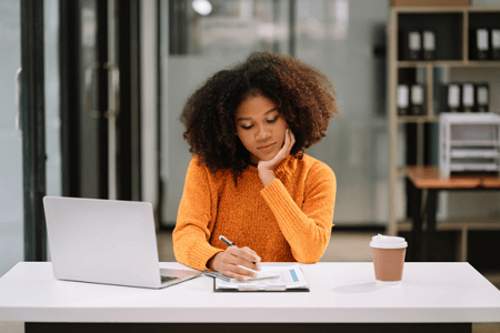 Young woman taking notes about how AI can help her learn to code in HTML.