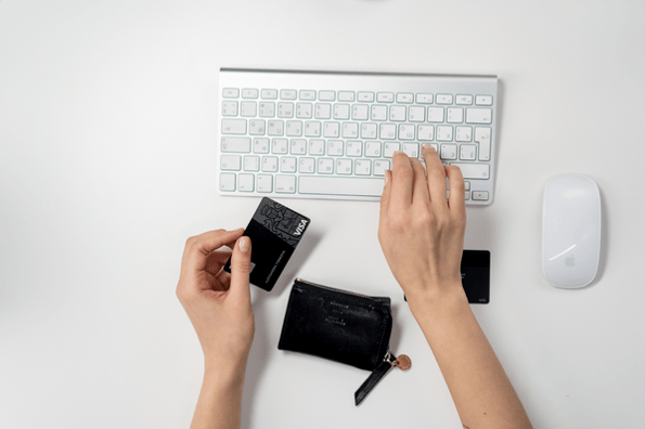 personne entrain de taper sur son clavier, carte bancaire à la main 