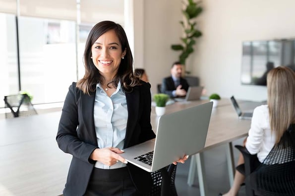 Unternehmensführerin hält Laptop in der Hand und lächelt in Kamera