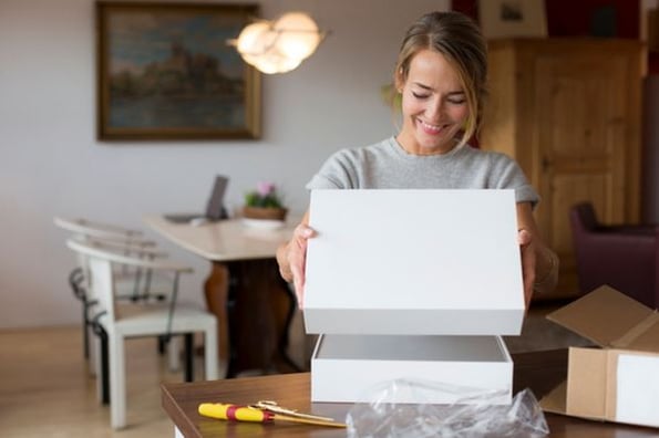 Kundin öffnet Paket, das sie dank Curated Shopping nach Hause geliefert bekommen hat