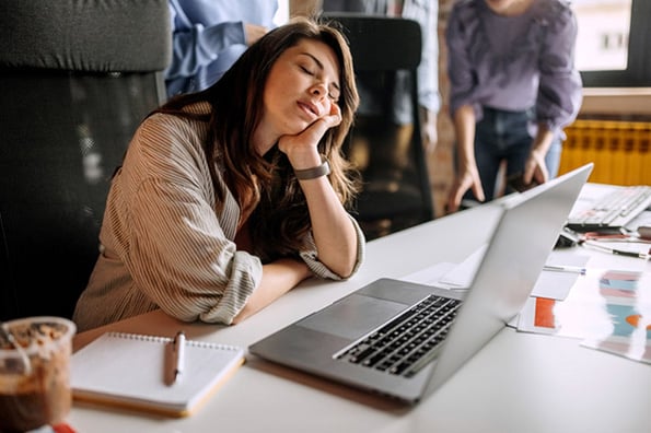 Schlafende Frau vor Laptop leidet an Demotivation bei der Arbeit