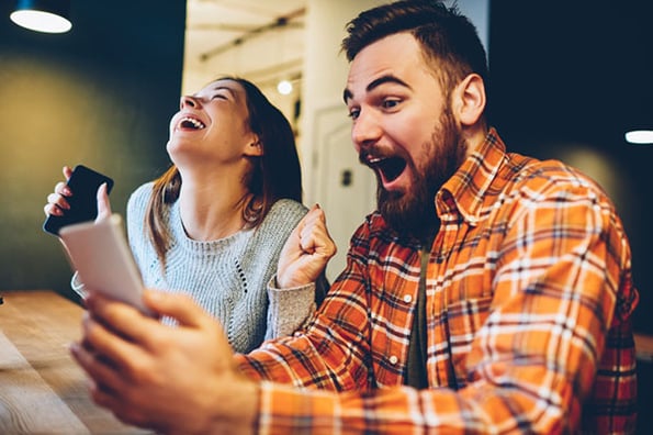 Mann und Frau gucken sich witzige Memes auf Smartphone an