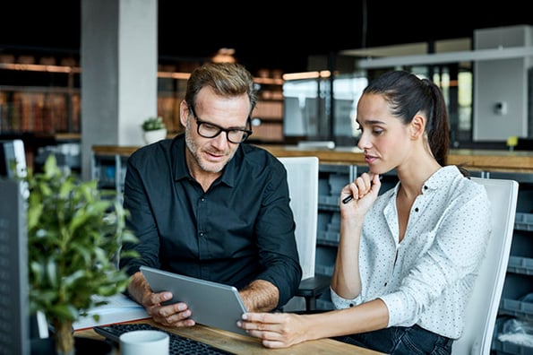 Frau und Mann schauen auf Tablet und besprechen Produktanalyse