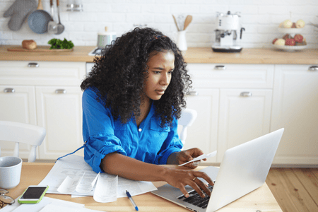 Woman studying pandas dataframe sorting on her computer in her kitchen.