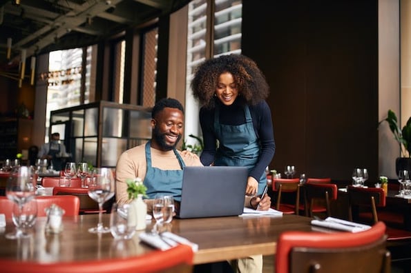 two people looking at restaurant website examples on a laptop in a cafe