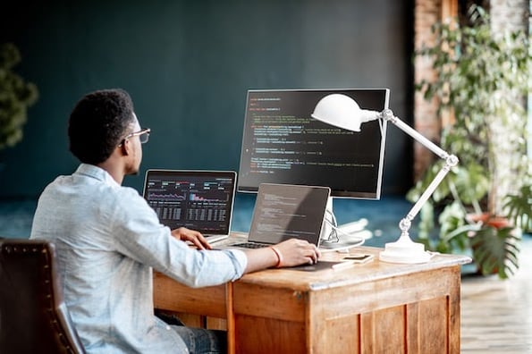 man using a desktop computer and a tablet to write a web page in accordance with HTML accessibility principles