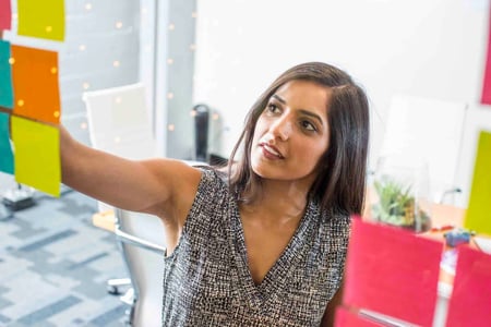 woman using post it notes to do a competitor analysis