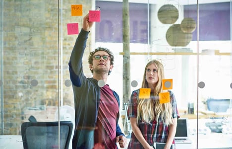 two people reviewing project management basics on a whiteboard 