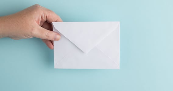 Hand holding white envelope on teal background