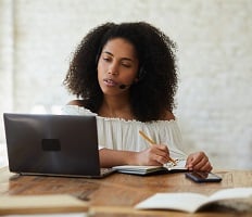 person using a laptop and taking notes