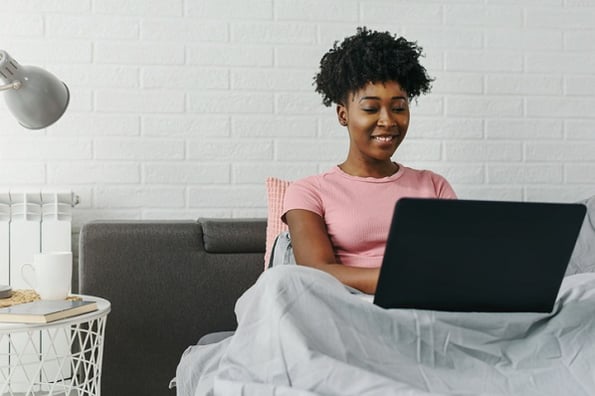 A woman sits at home studying Python lists by practicing at home on her computer.