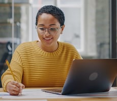 person using a laptop and writing notes