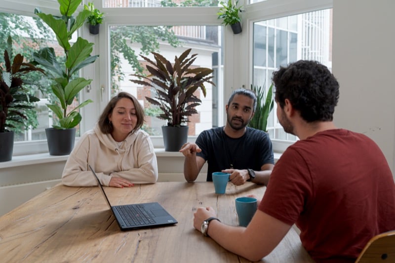 3 people talking around a laptop