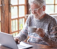 person using a laptop and holding a cup