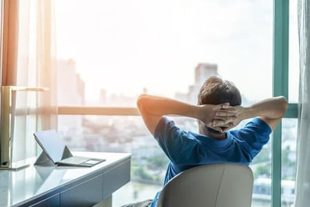 a business person gets distracted by looking out the window at his office during a summer slump.