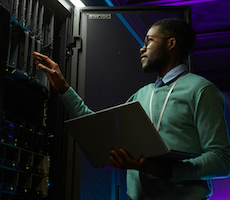 person using a laptop in a server room