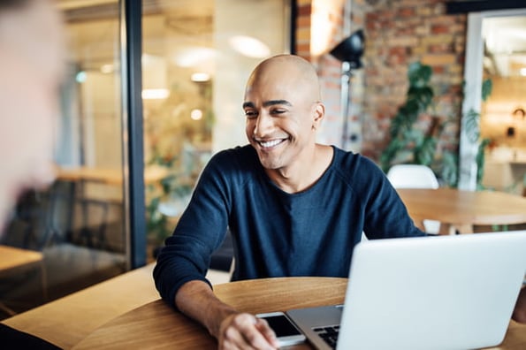 Person in office cafeteria with their laptop deciding between Bluehost vs WordPress