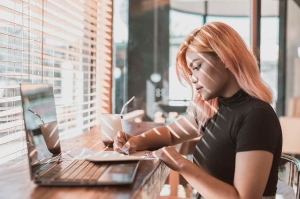 A woman takes notes while observing CDPs, CRMs, and DMPs on her laptop. 