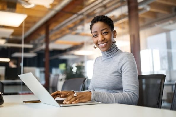 Woman at laptop smiles as she distributes her content effectively.