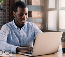 man using a laptop and smiling