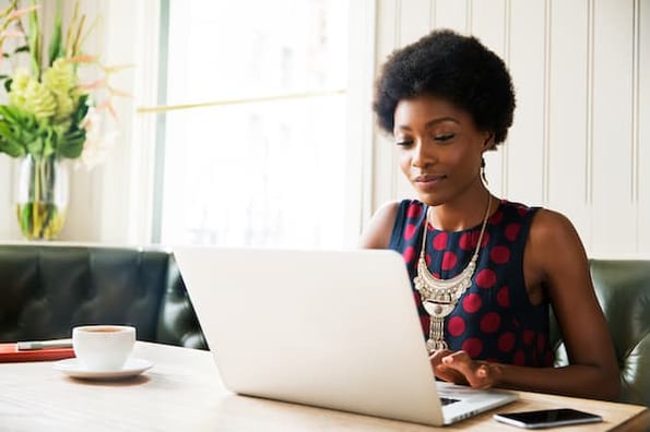 Woman using computer to learn the difference between CSS Grid vs. Flexbox