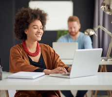 person using a laptop at a desk and smiling