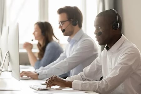 benefits of customer surveys: image shows three customer service reps on computer and talking on phone