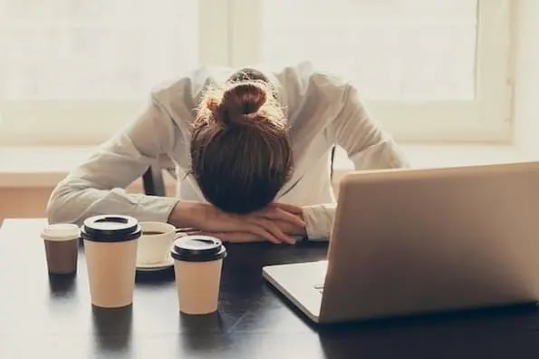 customer support rep leaned over desk with head on hands dealing with burnout