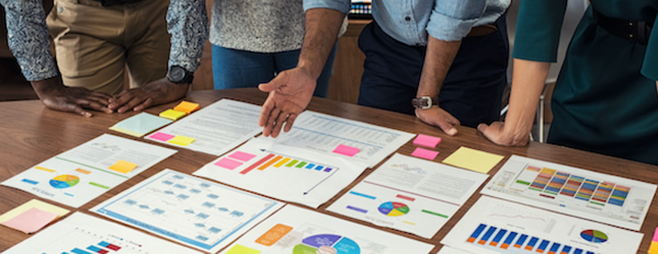 a group looking at charts laid out on a table