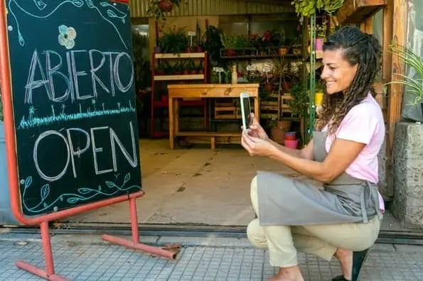 woman taking photo with phone of store sign for pinterest marketing