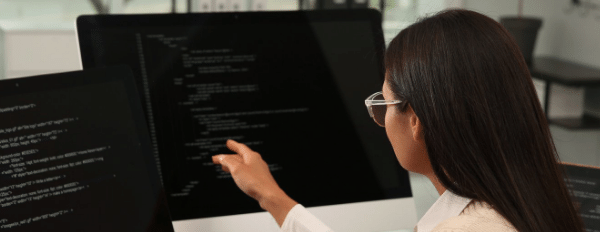 person viewing code on two desktop computers