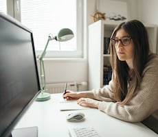 woman writing code on a desktop computer