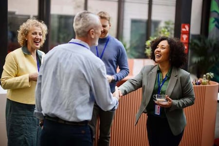 woman practicing networking skills at an event and shaking someone’s hand