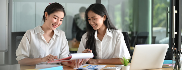 two people looking at documents at a desk in an office