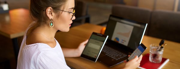 person holding a phone and a tablet while sitting at a desk