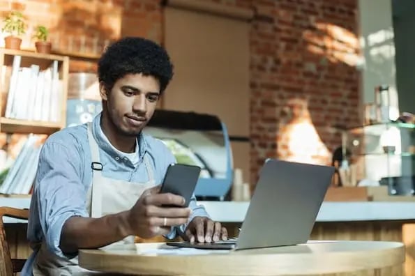 person using a laptop and a smartphone to review small business website design examples