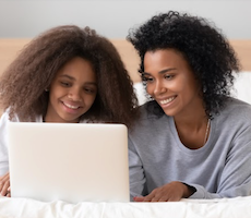 an adult and child using a laptop and smiling