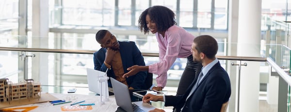 three people using computers in an office