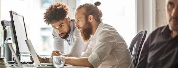 two people using a laptop in an office