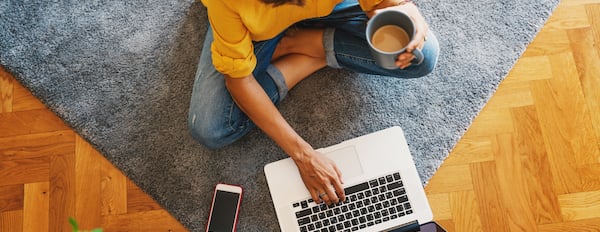 person using a laptop and sitting on the floor