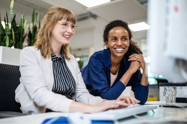 Coworkers discuss what a page title is in SEO while looking at examples on a computer.