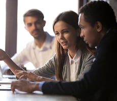 three people using a computer in an office