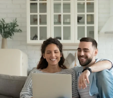 two people using a laptop on a couch