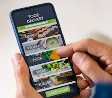 close-up of hands holding a smartphone showing a delivery app